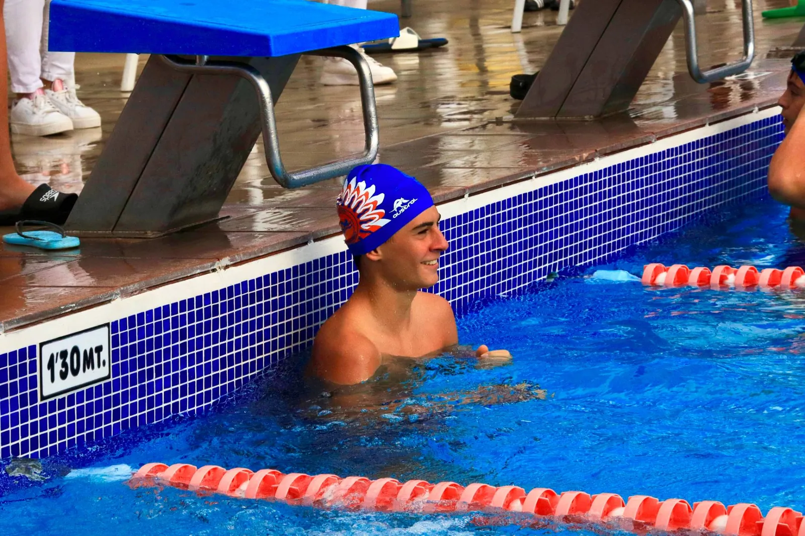 Nadador del club sonriendo junto a la pared de la piscina
