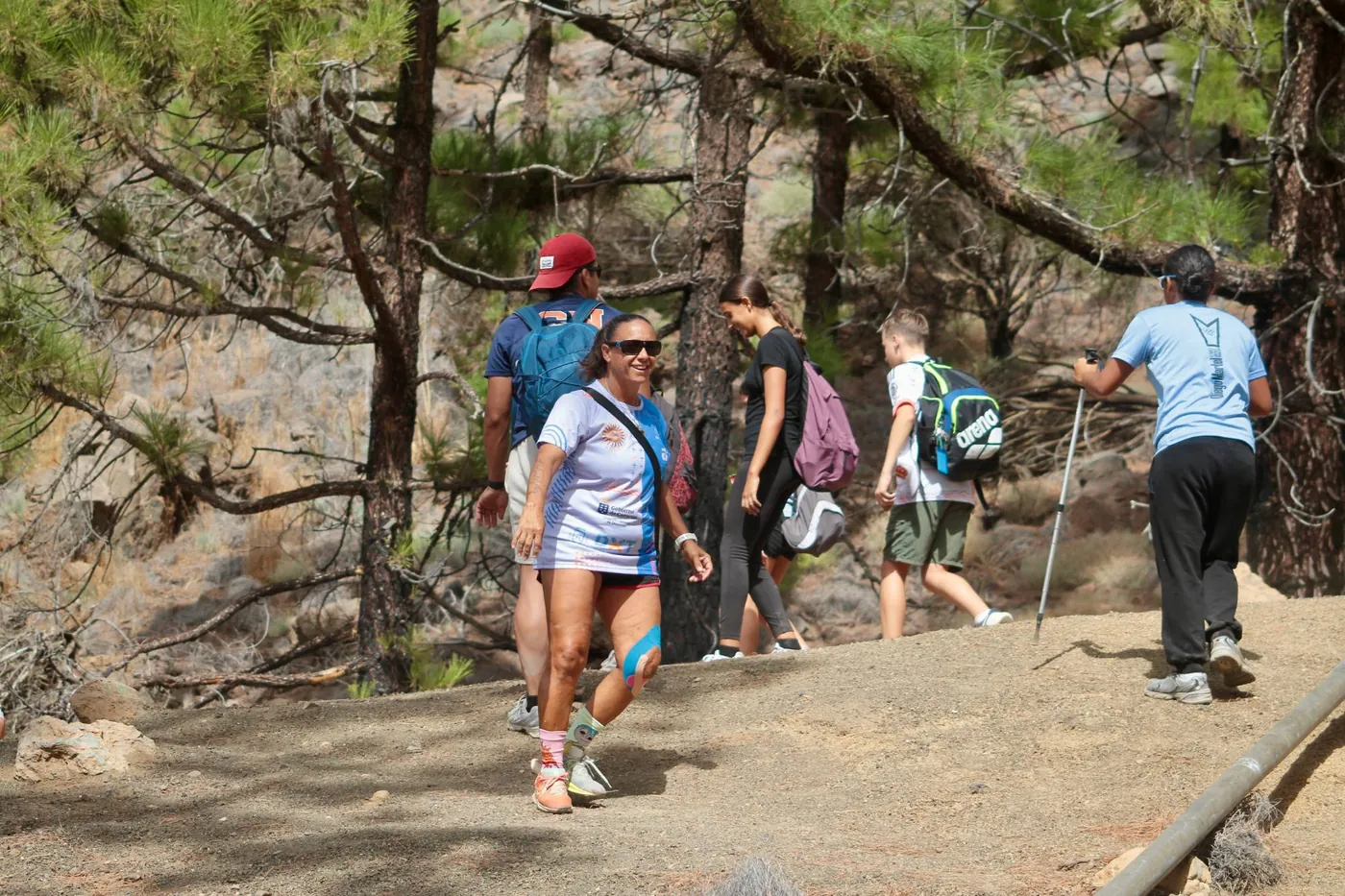 María Asencio caminando con el grupo por el sendero entre pinos
