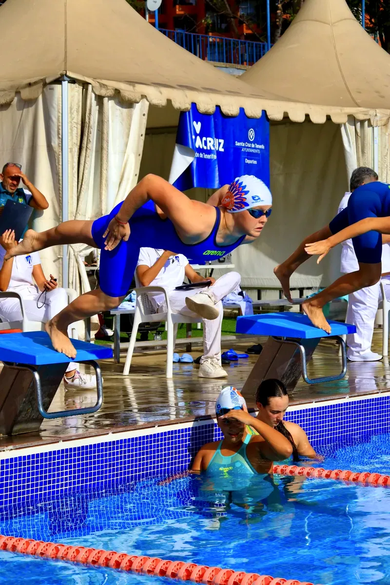 Nadadora del club saltando desde el poyete en una competición